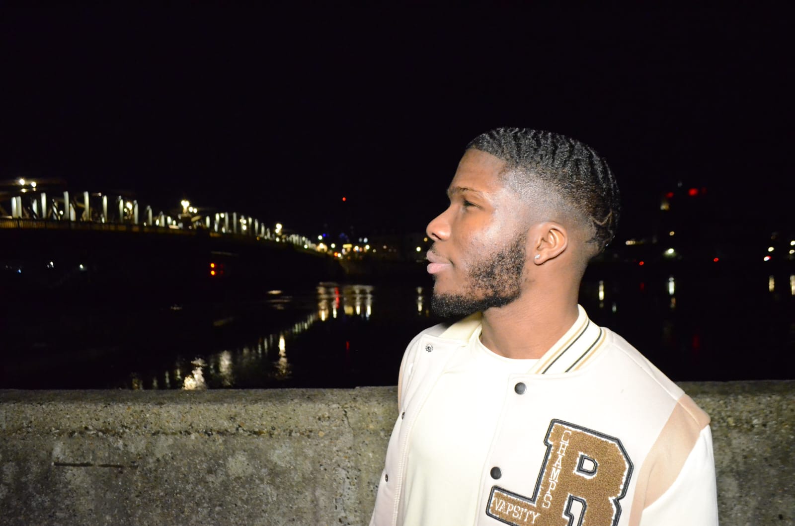 Jeremiah Bekoe looking in the distance at night by the Espinade in Rochester
